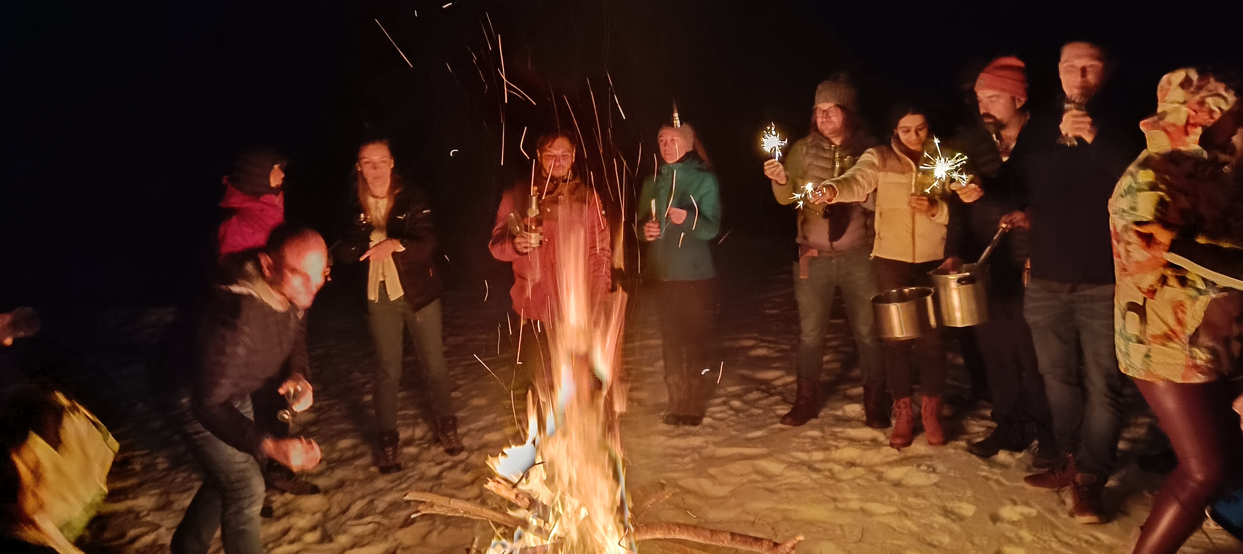 Hiking Buddies celebrating around a fire in the snow